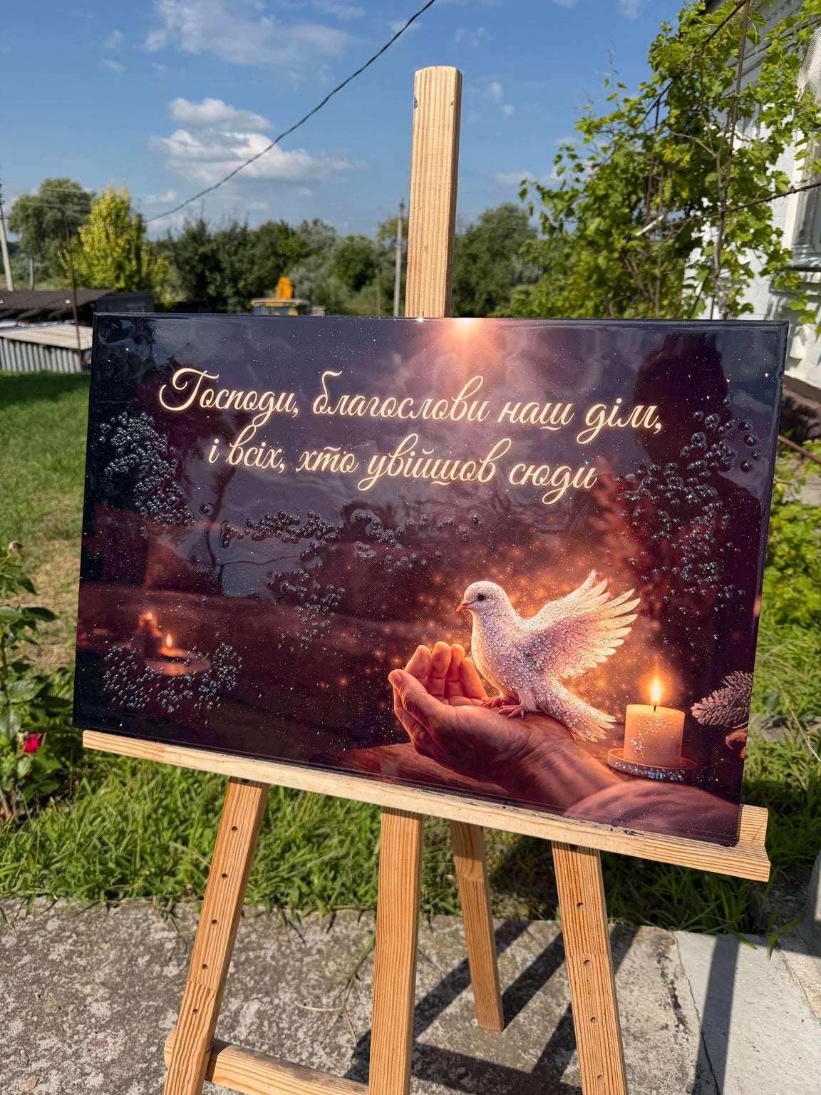 Руки тримають білого голуба поруч зі свічкою та написом Господи благослови наш дім